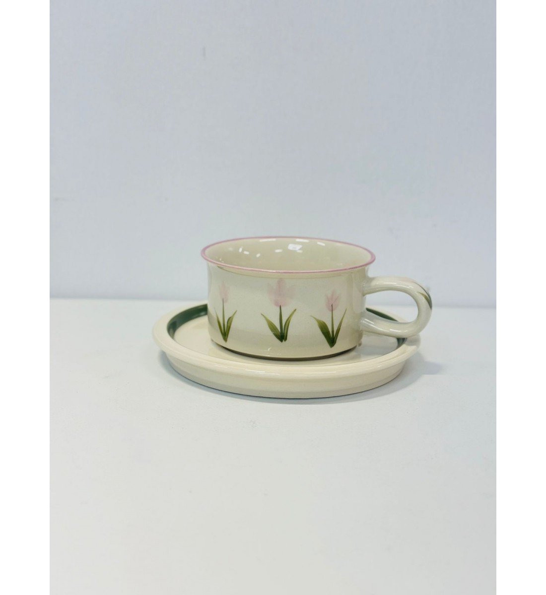 هذا طقم راقٍ مكوّن من فنجان وصحن خزفي بتصميم بسيط وأنيق. يأتي باللون العاجي الفاتح مع لمسات من الزهور الوردية الفاتحة المرسومة