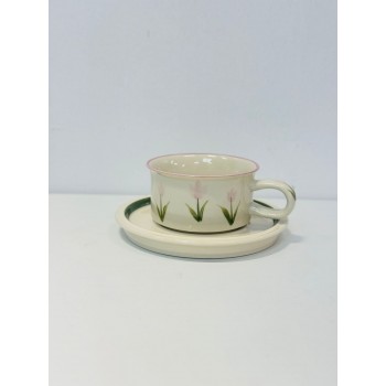 هذا طقم راقٍ مكوّن من فنجان وصحن خزفي بتصميم بسيط وأنيق. يأتي باللون العاجي الفاتح مع لمسات من الزهور الوردية الفاتحة المرسومة