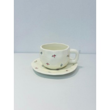 طقم خزفي أنيق مكوّن من فنجان وصحن بتصميم يدوي ناعم.يأتي باللون الأبيض العاجي مع لمسات زخرفية صغيرة لزهور ملونة باللونين الوردي والأزرق