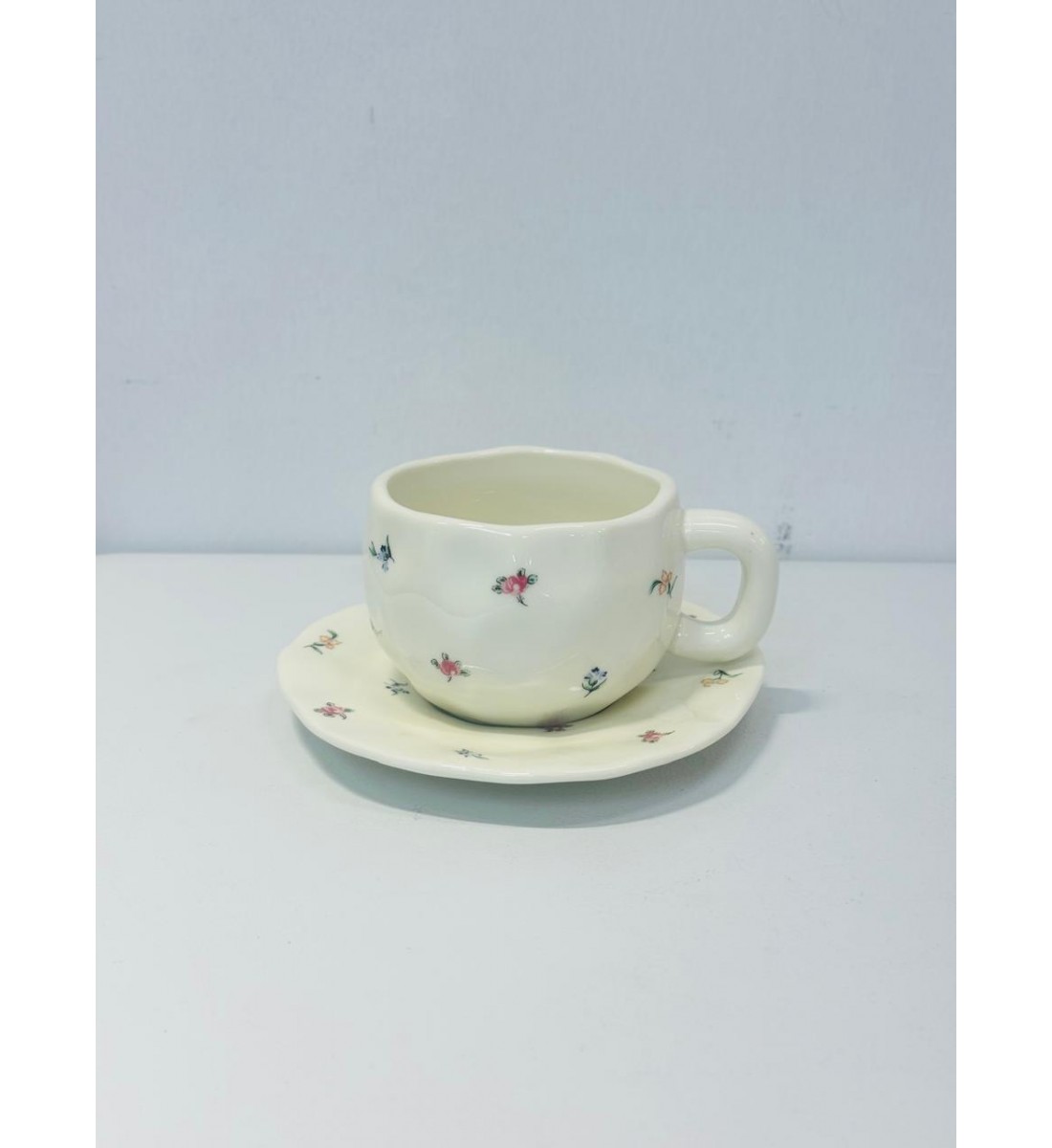 طقم خزفي أنيق مكوّن من فنجان وصحن بتصميم يدوي ناعم.يأتي باللون الأبيض العاجي مع لمسات زخرفية صغيرة لزهور ملونة باللونين الوردي والأزرق طقم خزفي أنيق مكوّن من فنجان وصحن بتصميم يدوي ناعم.يأتي باللون الأبيض العاجي مع لمسات زخرفية صغيرة لزهور ملونة باللونين الوردي والأزرق