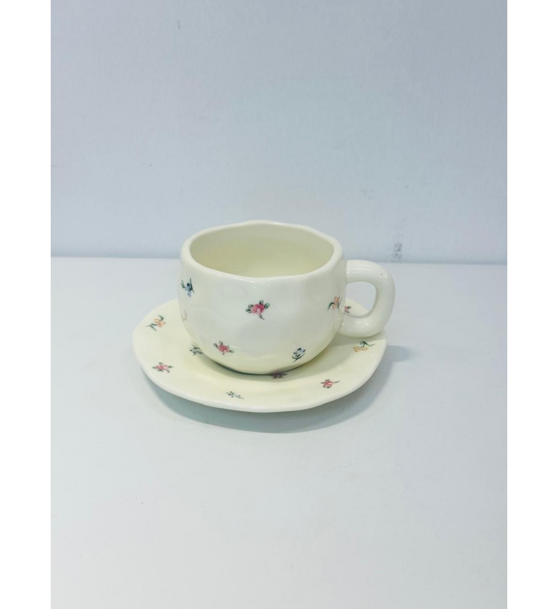 طقم خزفي أنيق مكوّن من فنجان وصحن بتصميم يدوي ناعم.يأتي باللون الأبيض العاجي مع لمسات زخرفية صغيرة لزهور ملونة باللونين الوردي والأزرق طقم خزفي أنيق مكوّن من فنجان وصحن بتصميم يدوي ناعم.يأتي باللون الأبيض العاجي مع لمسات زخرفية صغيرة لزهور ملونة باللونين الوردي والأزرق