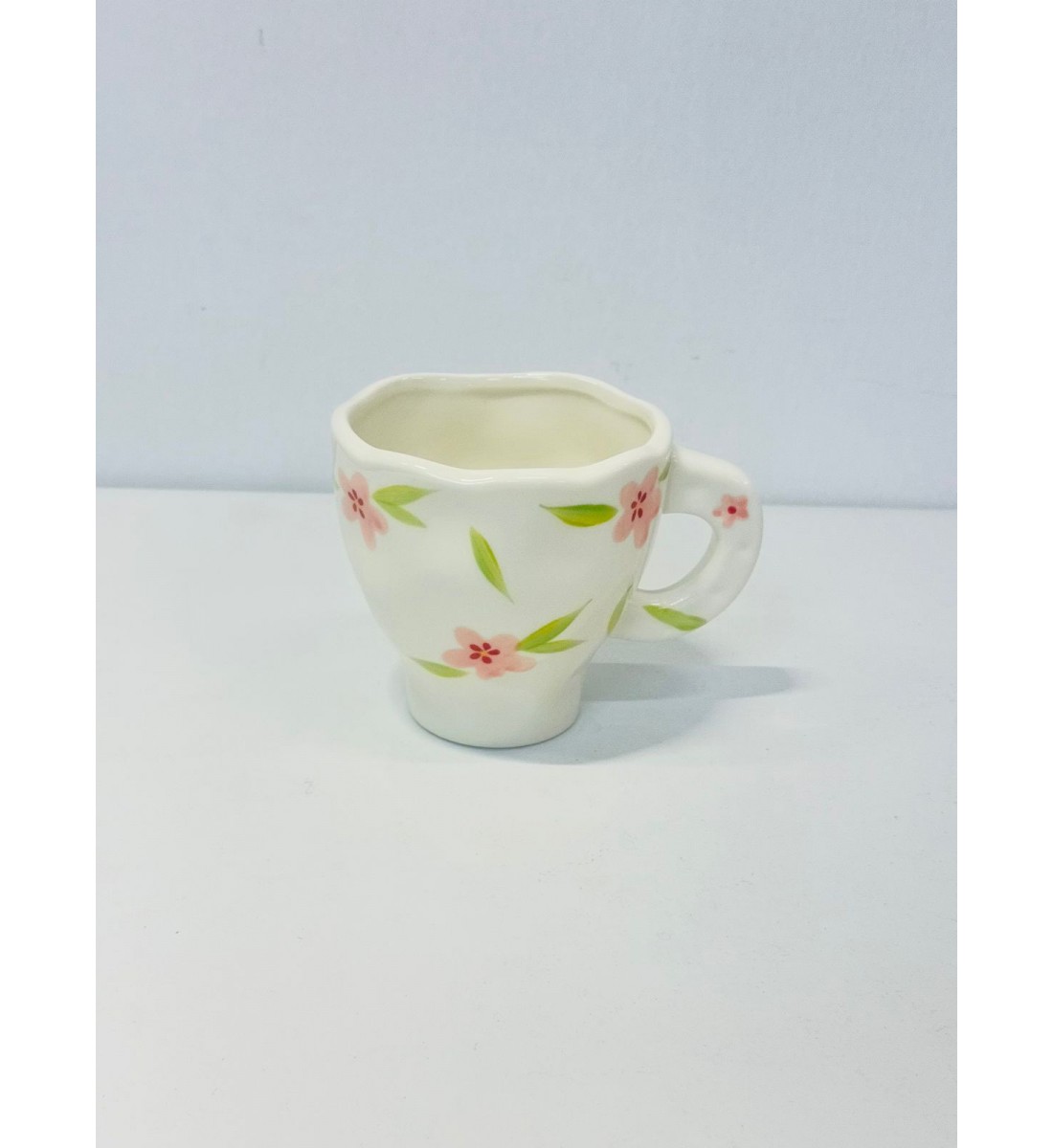 هذا كوب سيراميك أنيق بتصميم فريد يحمل لمسة يدوية راقية أبيض العاجي مزين برسومات زهرية رقيقة باللون الورد والاخظر 