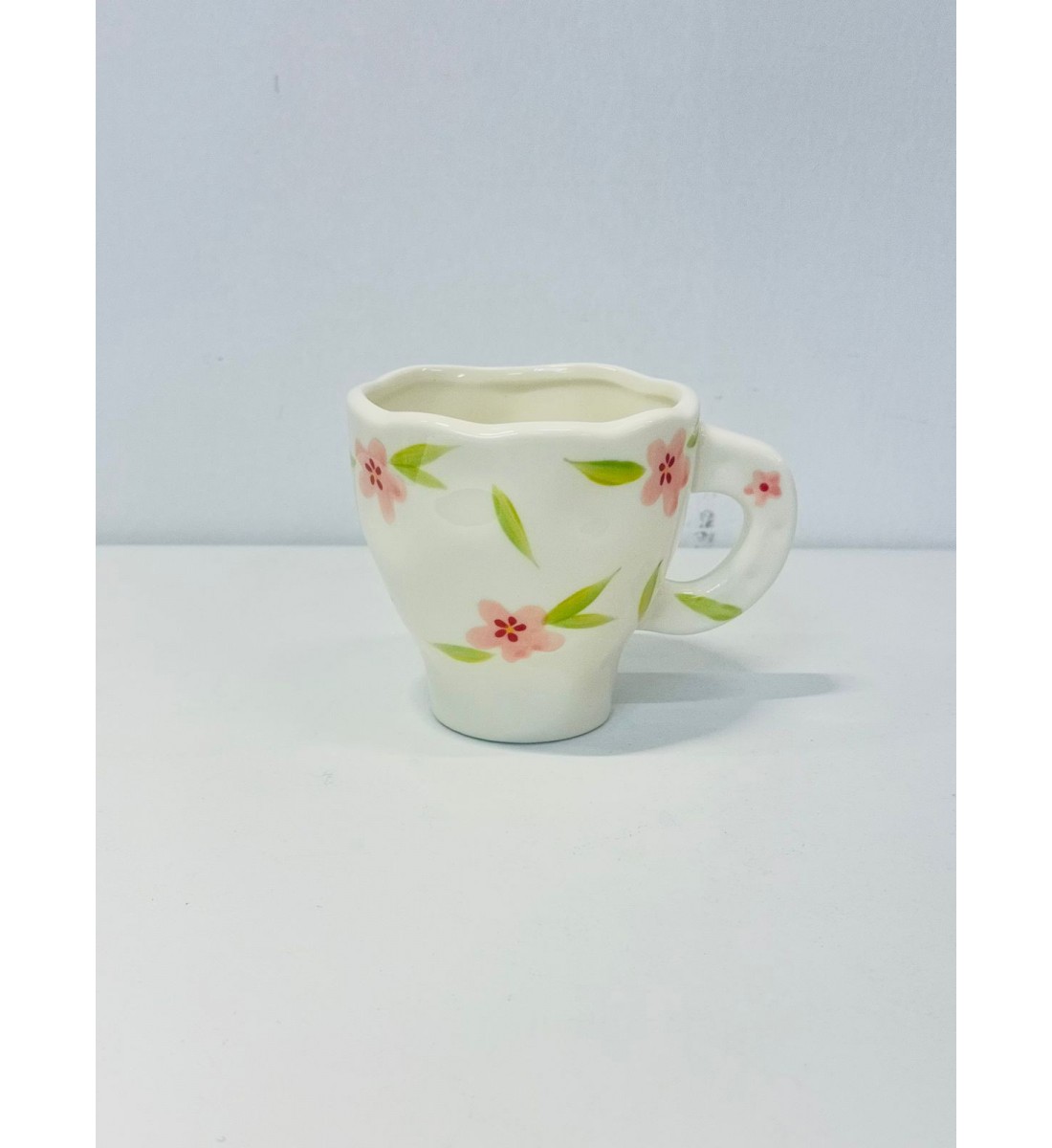 هذا كوب سيراميك أنيق بتصميم فريد يحمل لمسة يدوية راقية أبيض العاجي مزين برسومات زهرية رقيقة باللون الورد والاخظر 