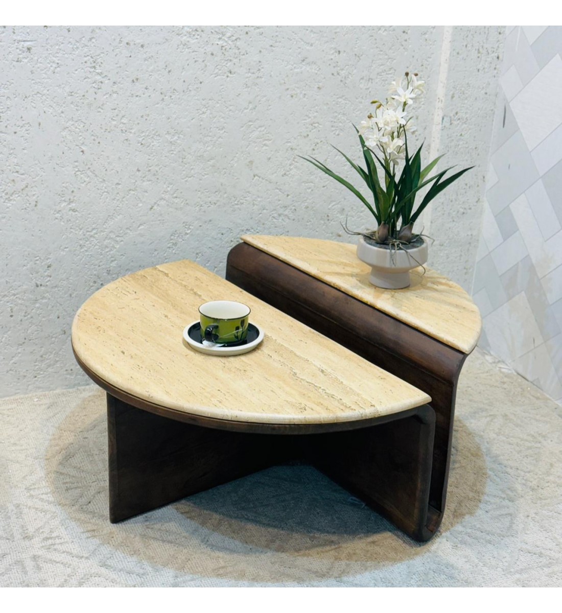 طاولة عصرية مكوّنة من قطعتين متشابكتين بتصميم فريد، يجمع بين السطح الرخامي الفاتح والقاعدة الخشبية الداكنة. 88×83×40سم 