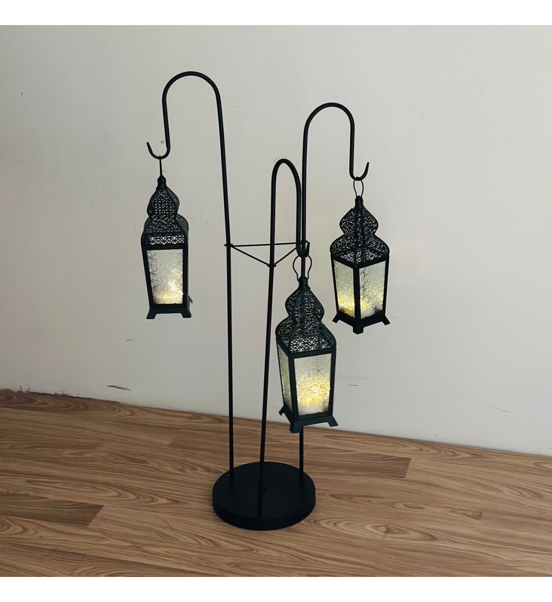 قطعة ديكورية أنيقة بتصميم عمودي مميّز، تتكوّن من حامل معدني أسود يحمل ثلاثة فوانيس معلّقة بنقوش شرقية دقيقة وزجاج يعطي إضاءة دافئة وناعمة 102×40×40سم قطعة ديكورية أنيقة بتصميم عمودي مميّز، تتكوّن من حامل معدني أسود يحمل ثلاثة فوانيس معلّقة بنقوش شرقية دقيقة وزجاج يعطي إضاءة دافئة وناعمة 102×40×40سم