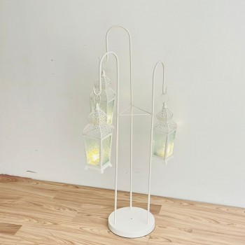 قطعة ديكورية أنيقة بتصميم عمودي مميّز، تتكوّن من حامل معدني ابيض يحمل ثلاثة فوانيس معلّقة بنقوش شرقية دقيقة وزجاج يعطي إضاءة دافئة وناعمة 102×40×40سم 