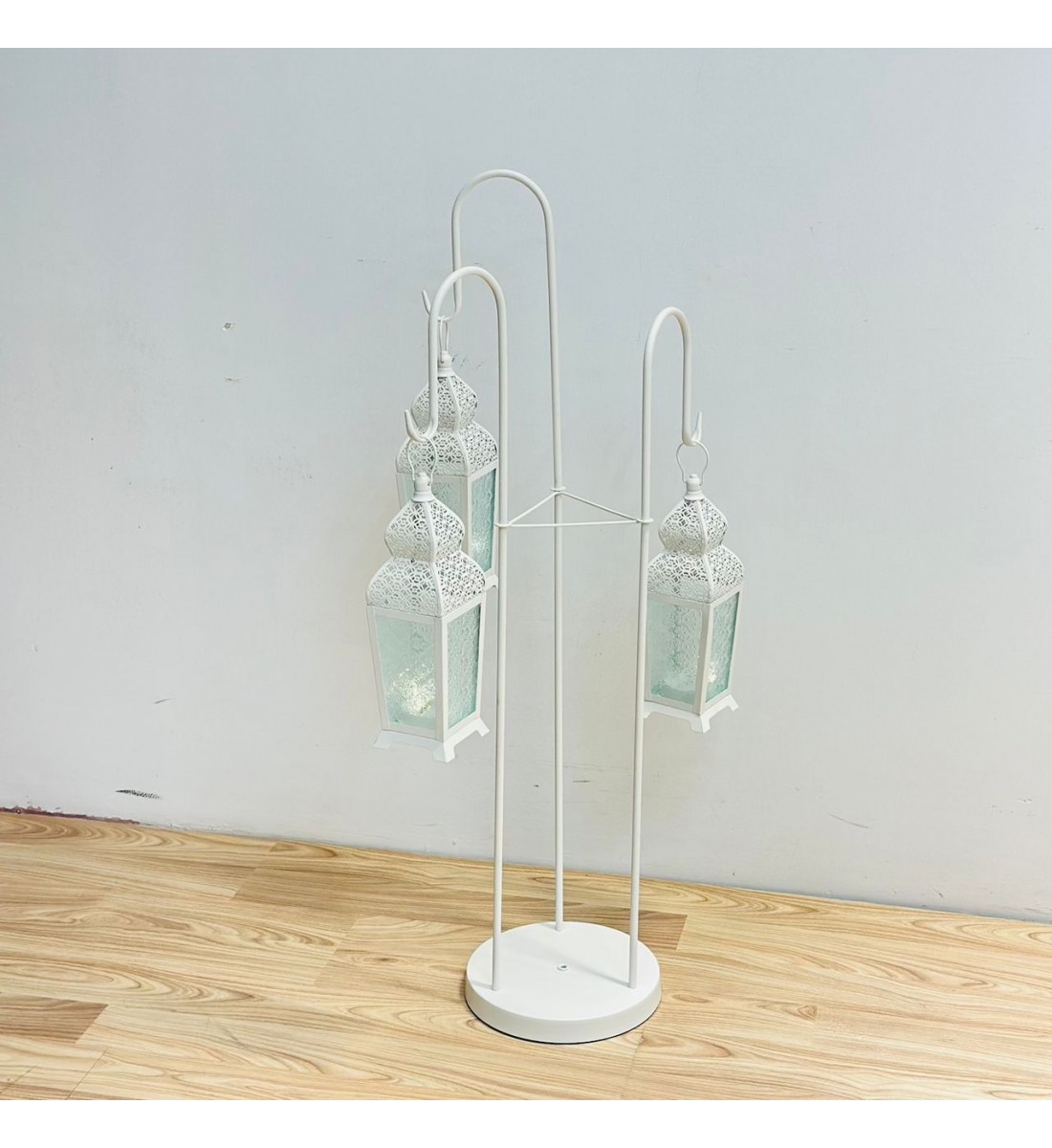 قطعة ديكورية أنيقة بتصميم عمودي مميّز، تتكوّن من حامل معدني ابيض يحمل ثلاثة فوانيس معلّقة بنقوش شرقية دقيقة وزجاج يعطي إضاءة دافئة وناعمة 102×40×40سم قطعة ديكورية أنيقة بتصميم عمودي مميّز، تتكوّن من حامل معدني ابيض يحمل ثلاثة فوانيس معلّقة بنقوش شرقية دقيقة وزجاج يعطي إضاءة دافئة وناعمة 102×40×40سم