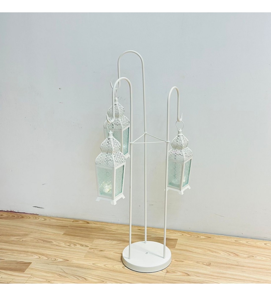 قطعة ديكورية أنيقة بتصميم عمودي مميّز، تتكوّن من حامل معدني ابيض يحمل ثلاثة فوانيس معلّقة بنقوش شرقية دقيقة وزجاج يعطي إضاءة دافئة وناعمة 102×40×40سم قطعة ديكورية أنيقة بتصميم عمودي مميّز، تتكوّن من حامل معدني ابيض يحمل ثلاثة فوانيس معلّقة بنقوش شرقية دقيقة وزجاج يعطي إضاءة دافئة وناعمة 102×40×40سم