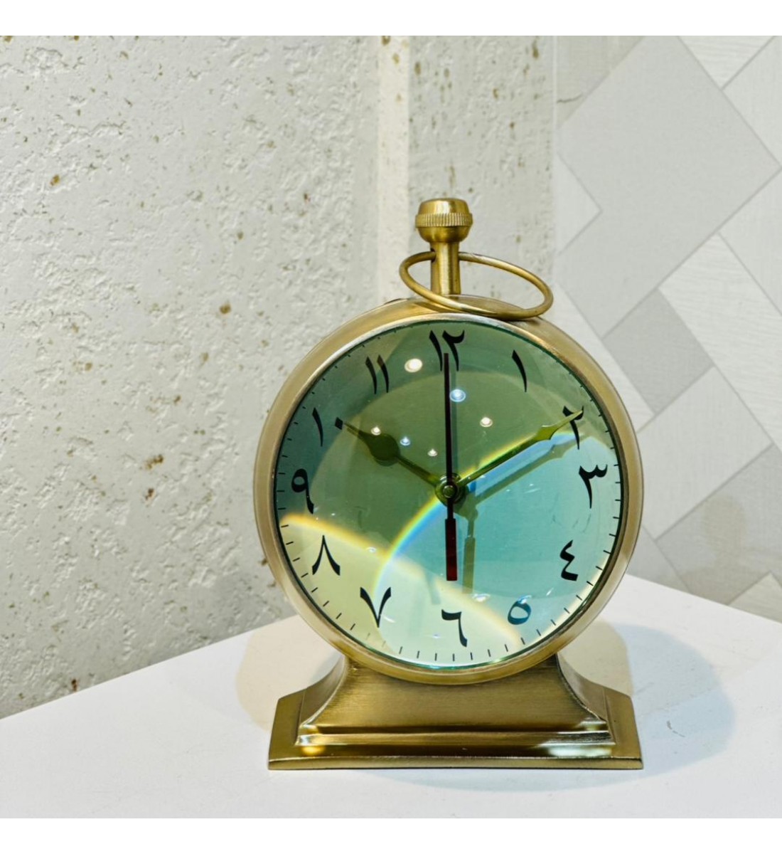  ساعة ديكورية أنيقة بتصميم كلاسيكي فاخر، مصنوعة من المعدن باللون الذهبي مع قاعدة ثابتة تعزز من فخامتها.  26×20سم 