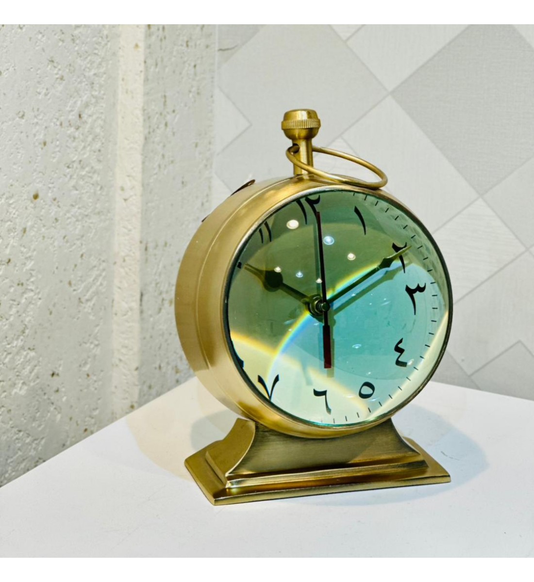  ساعة ديكورية أنيقة بتصميم كلاسيكي فاخر، مصنوعة من المعدن باللون الذهبي مع قاعدة ثابتة تعزز من فخامتها.  26×20سم 
