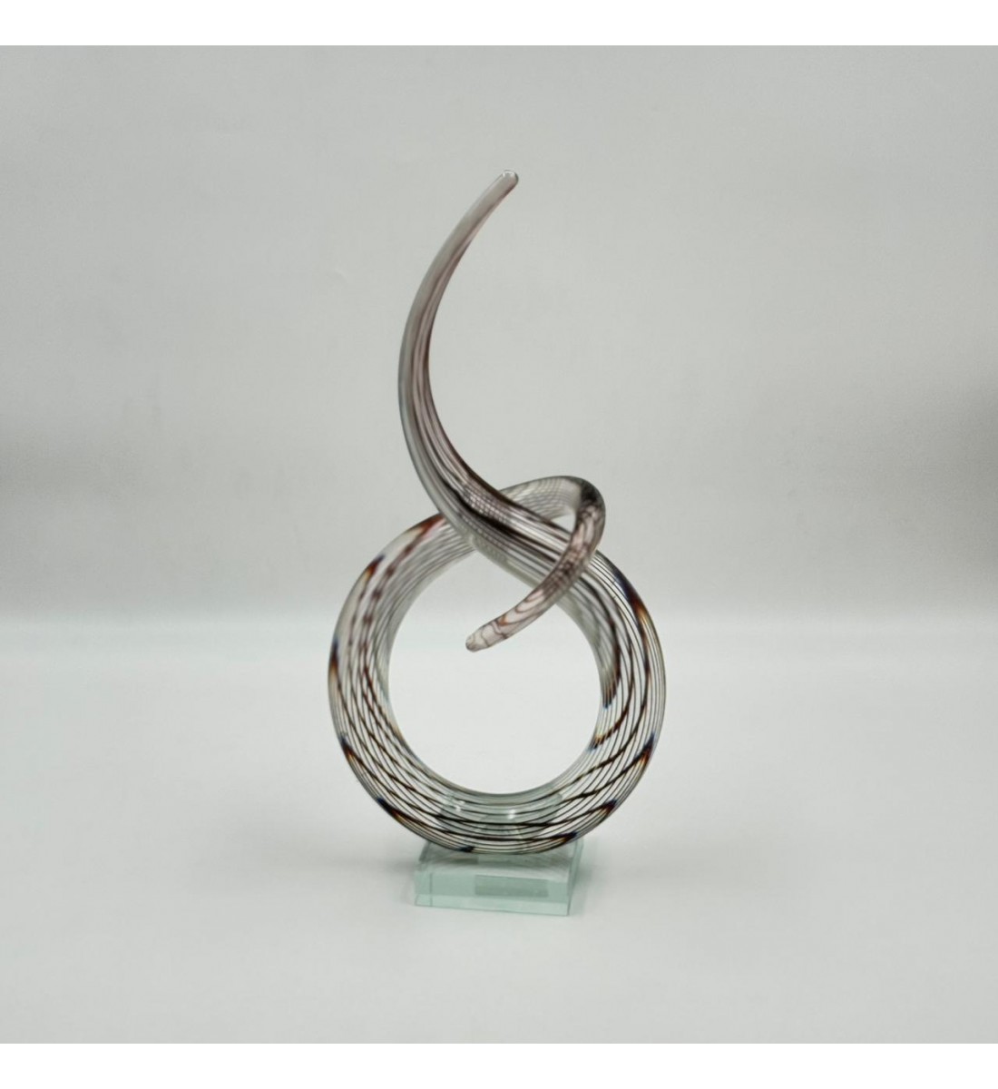 A decorative art piece made of clear glass with a streamlined design inspired by the musical note symbol, 33 x 13 x 8 cm