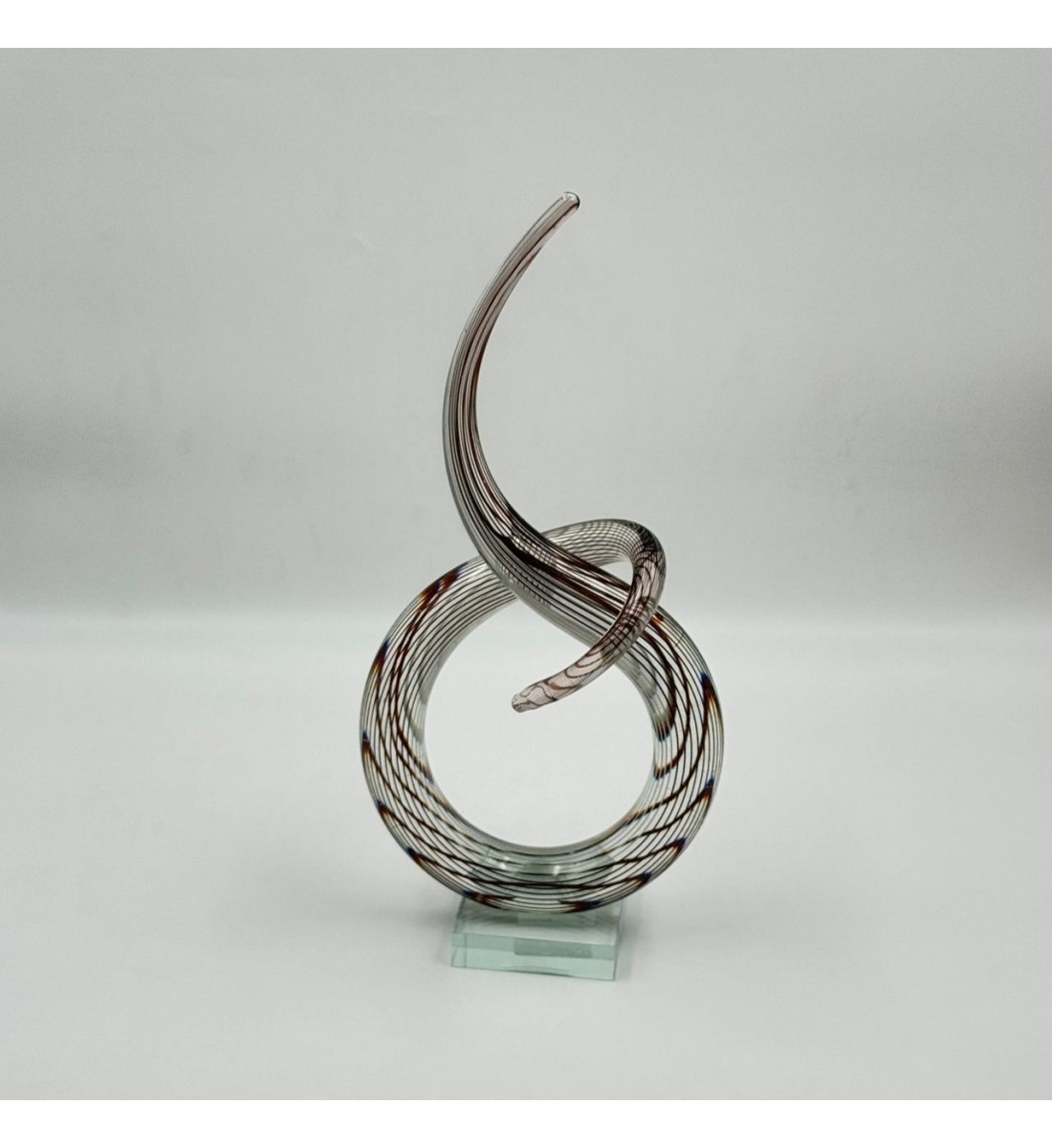 A decorative art piece made of clear glass with a streamlined design inspired by the musical note symbol, 33 x 13 x 8 cm